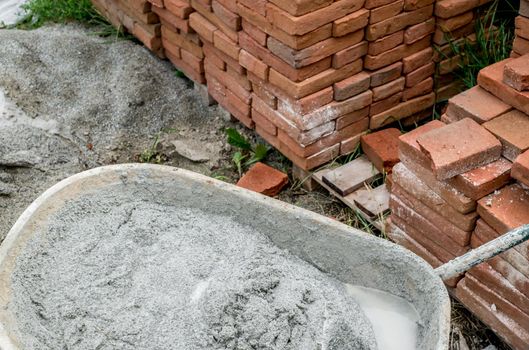 wheelbarrow with abandoned plaster next to a pile of bricks