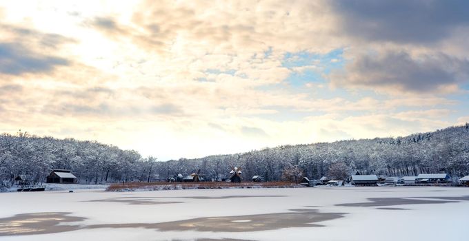 Winter panorama with windmills and frozen lake in a cloudy cold day
