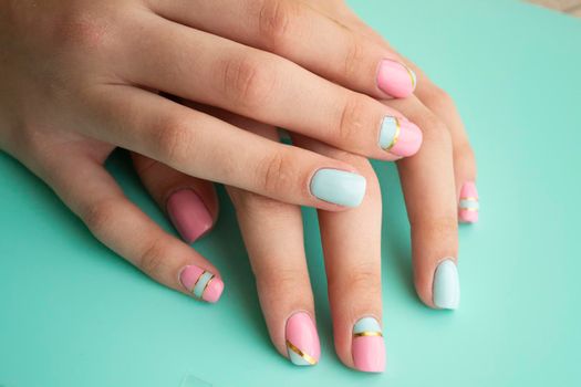 Women hands with a stylish manicure in teal or blue and pink