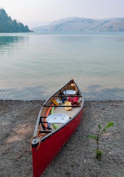 Red lightweight canoe boat on a shore of Kalamalka lake on foggy day