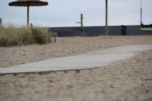 Close-up of a sandy beach with a wooden path on a cold day