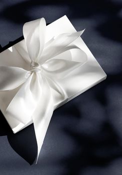 Anniversary celebration, shop sale promotion and luxe surprise concept - Luxury holiday white gift box with silk ribbon and bow on black background, luxe wedding or birthday present