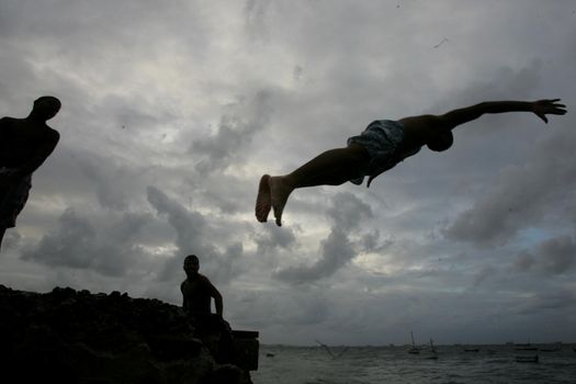 salvador, bahia, brazil - may 10, 2013: Young people jump from the breakwater at Forte de santa Maria, in Porto da Barra in the city of Salvador.