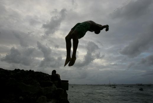 salvador, bahia, brazil - may 10, 2013: Young people jump from the breakwater at Forte de santa Maria, in Porto da Barra in the city of Salvador.