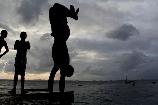 salvador, bahia, brazil - may 10, 2013: Young people jump from the breakwater at Forte de santa Maria, in Porto da Barra in the city of Salvador.