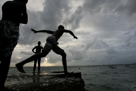 salvador, bahia, brazil - may 10, 2013: Young people jump from the breakwater at Forte de santa Maria, in Porto da Barra in the city of Salvador.