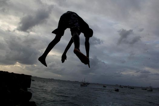 salvador, bahia, brazil - may 10, 2013: Young people jump from the breakwater at Forte de santa Maria, in Porto da Barra in the city of Salvador.