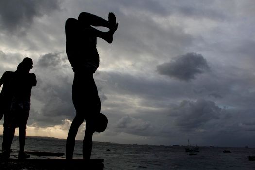 salvador, bahia, brazil - may 10, 2013: Young people jump from the breakwater at Forte de santa Maria, in Porto da Barra in the city of Salvador.