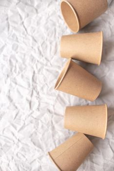 disposable kraft paper cups laid out on gray crumpled paper in geometric pattern