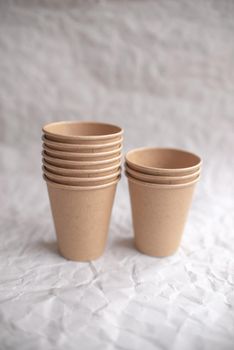 disposable kraft paper cups laid out on gray crumpled paper in geometric pattern