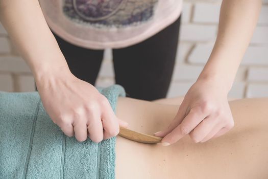 therapeutic back massage in the spa salon makes the girl a massage with wooden knives