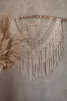 bouquet of reed plant on the background of a gray concrete wall with handmade macrame