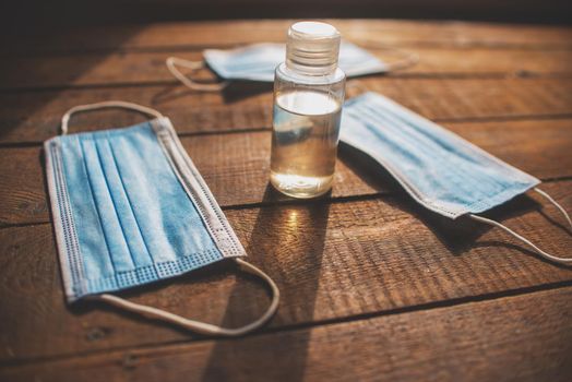 plastic bottle with hand sanitizer and disposable masks lie on a wooden table