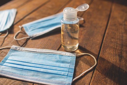 plastic bottle with hand sanitizer and disposable masks lie on a wooden table