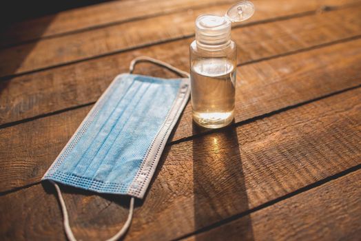 plastic bottle with hand sanitizer and disposable masks lie on a wooden table