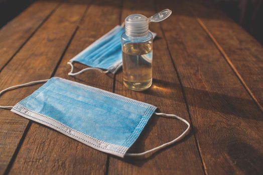 plastic bottle with hand sanitizer and disposable masks lie on a wooden table