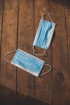 protective medical disposable masks in blue lie on a wooden table