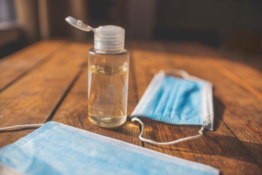 plastic bottle with hand sanitizer and disposable masks lie on a wooden table