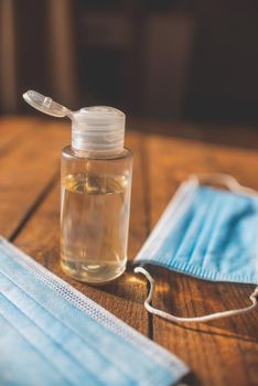 plastic bottle with hand sanitizer and disposable masks lie on a wooden table