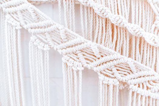 handmade macrame pattern a fragment of a wall panel in the boho style of beige cotton threads of natural color using the technique for home and wedding decor