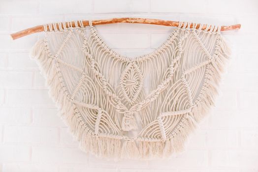 handmade macrame pattern for wall panels in boho style from beige cotton threads of natural color using technique for home and wedding decor
