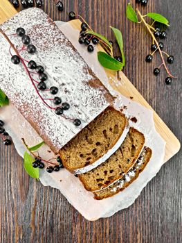 Fruitcake bird cherry cut with berries on a paper on the background of the wooden planks top