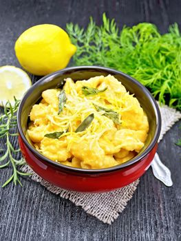 Pumpkin gnocchi with sage, lemon, cheese and butter in a bowl on burlap against dark wooden board