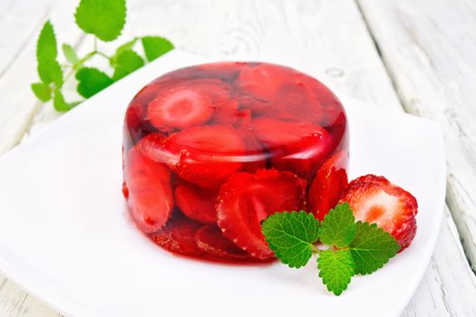 Strawberry jelly with mint and berries in a plate on a kitchen towel on the background light wooden boards