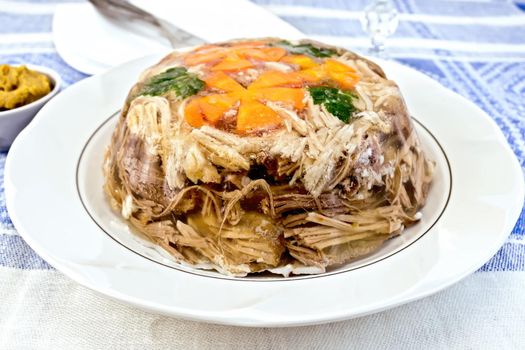 Jellied pork and beef with carrots and parsley on the plate on a mustard background of blue linen tablecloth