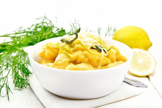 Pumpkin gnocchi with sage, lemon, cheese and butter in a bowl on a towel on the background of wooden boards