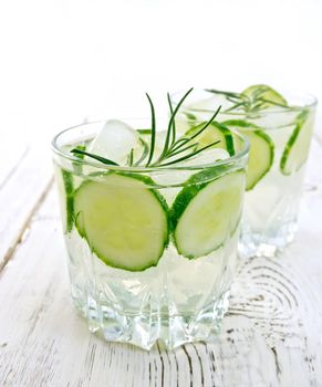 Lemonade with a cucumber and rosemary in two glassful on the background of wooden boards