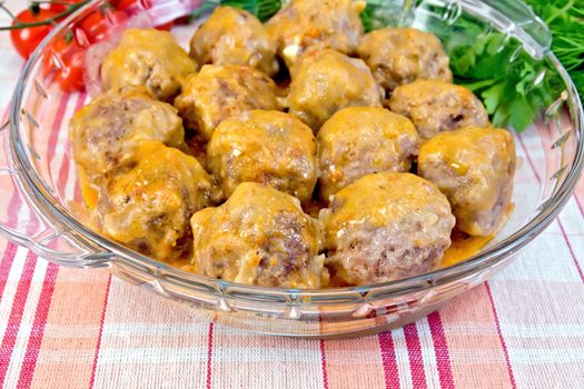 Meatballs with sauce in a glass pan, tomatoes, parsley on a linen tablecloth background