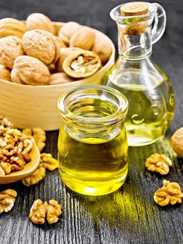 Walnut oil in a jar and decanter, nuts in a box, spoon and on table on wooden board background