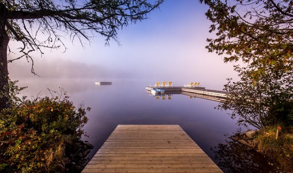 view of a boat dock the Lac-Superieur, misty morning with fog, in Laurentides, Mont-tremblant, Quebec, Canada