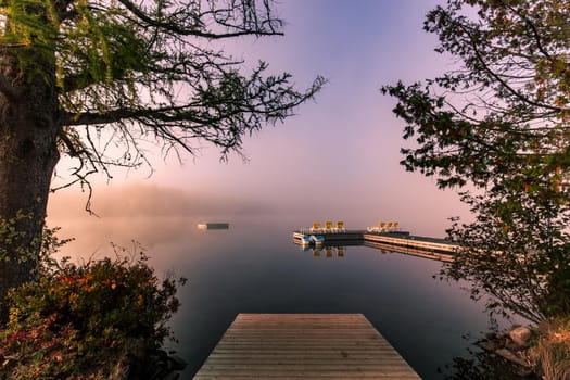 view of a boat dock the Lac-Superieur, misty morning with fog, in Laurentides, Mont-tremblant, Quebec, Canada