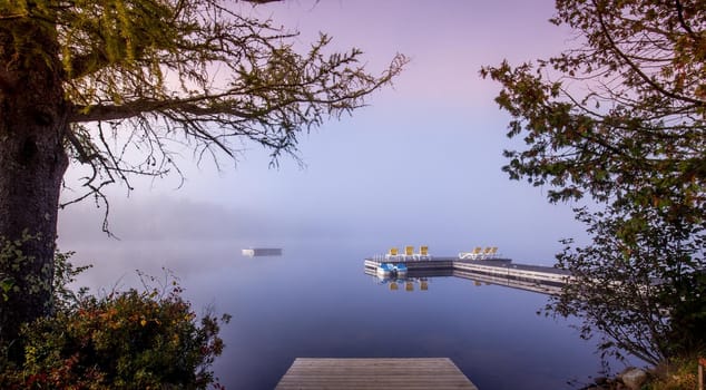 view of a boat dock the Lac-Superieur, misty morning with fog, in Laurentides, Mont-tremblant, Quebec, Canada