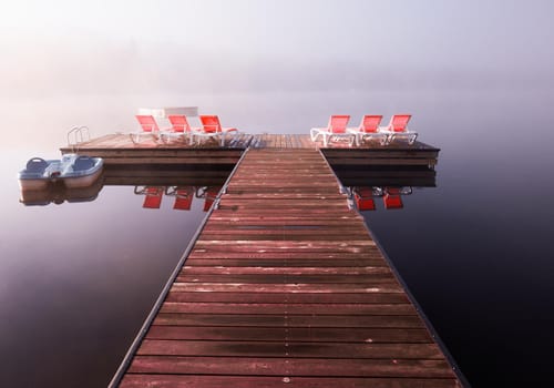 view of a boat dock the Lac-Superieur, misty morning with fog, in Laurentides, Mont-tremblant, Quebec, Canada