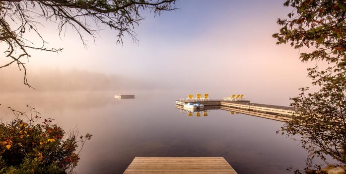 view of a boat dock the Lac-Superieur, misty morning with fog, in Laurentides, Mont-tremblant, Quebec, Canada