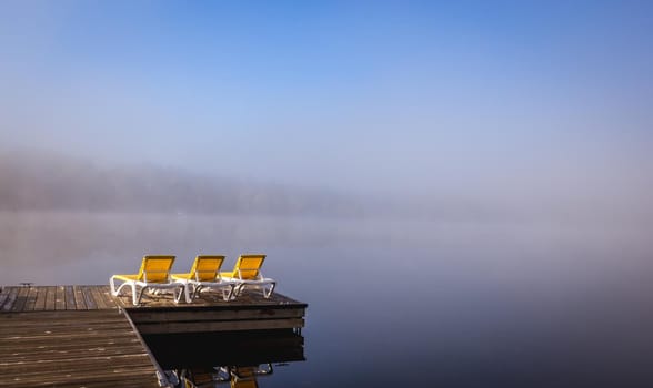 view of a boat dock the Lac-Superieur, misty morning with fog, in Laurentides, Mont-tremblant, Quebec, Canada