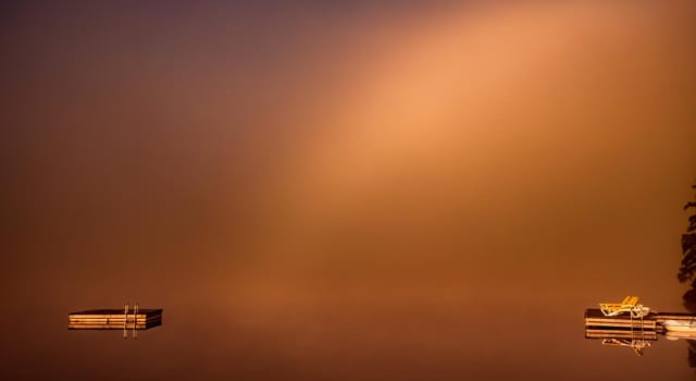 view of a boat dock the Lac-Superieur, misty morning with fog, in Laurentides, Mont-tremblant, Quebec, Canada