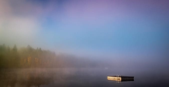 view of a boat dock the Lac-Superieur, misty morning with fog, in Laurentides, Mont-tremblant, Quebec, Canada