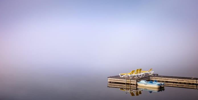 view of a boat dock the Lac-Superieur, misty morning with fog, in Laurentides, Mont-tremblant, Quebec, Canada