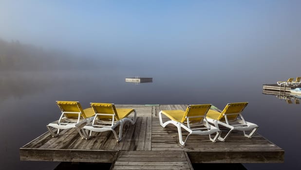 view of a boat dock the Lac-Superieur, misty morning with fog, in Laurentides, Mont-tremblant, Quebec, Canada