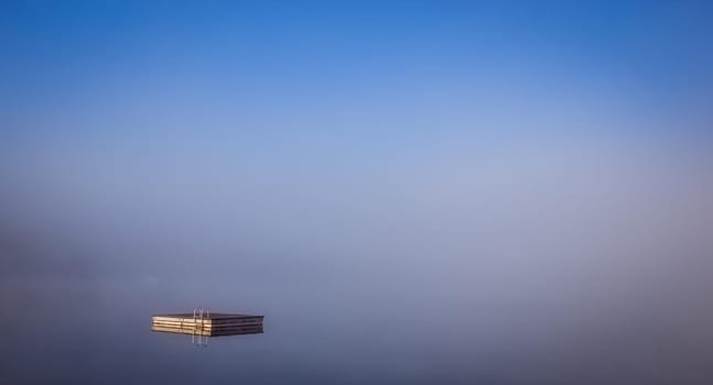 view of a boat dock the Lac-Superieur, misty morning with fog, in Laurentides, Mont-tremblant, Quebec, Canada