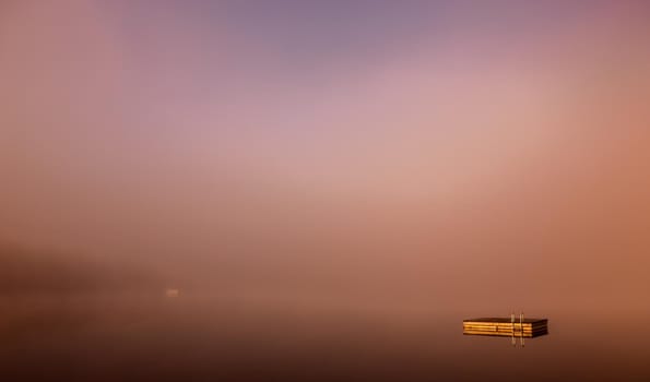 view of a boat dock the Lac-Superieur, misty morning with fog, in Laurentides, Mont-tremblant, Quebec, Canada