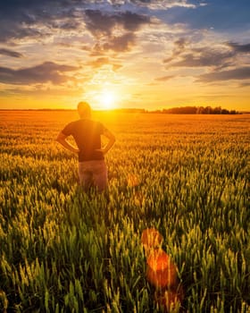 A man with folded hands at the waist against the background of sunset or dawn in a rye field. The concept of success, happiness, active lifestyle and outdoor recreation.