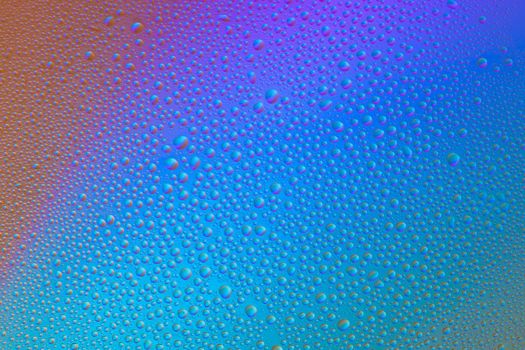 Colored abstract background from drops on glass. Rainbow color transitions.