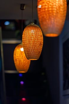 Orange lanterns in the form of a straw chandelier in a dim room.