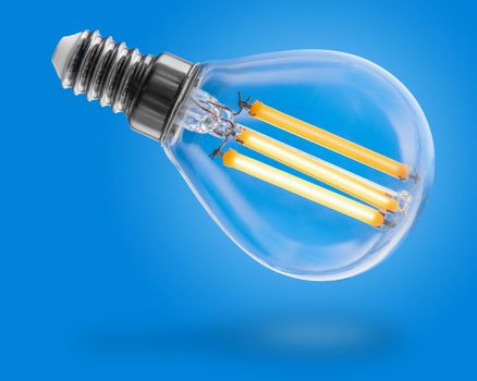 Energy efficient led filament Light Bulb Glowing isolated on blue background. Green Energy Concept