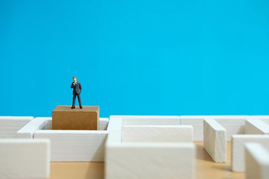 Business strategy conceptual photo - Miniature of businessman looking for solution on a labyrinth maze. Image photo